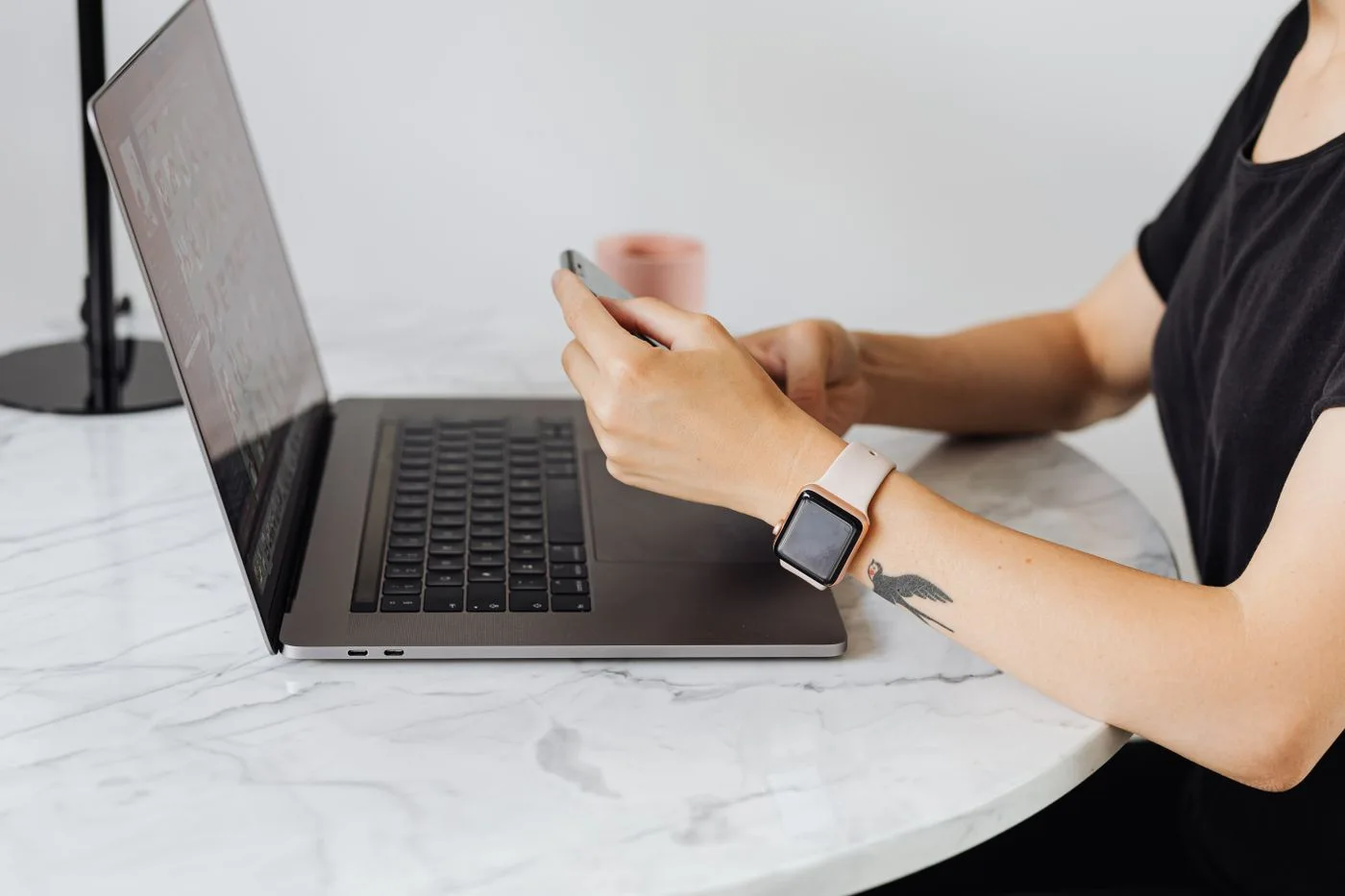 A person using a phone and laptop at a table.